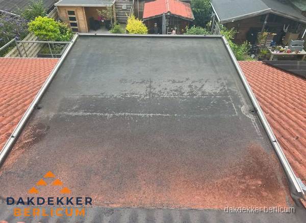Verouderd plat dak met slijtage tussen schuine daken in Berlicum Verouderd plat dak met slijtage tussen schuine daken in Berlicum
