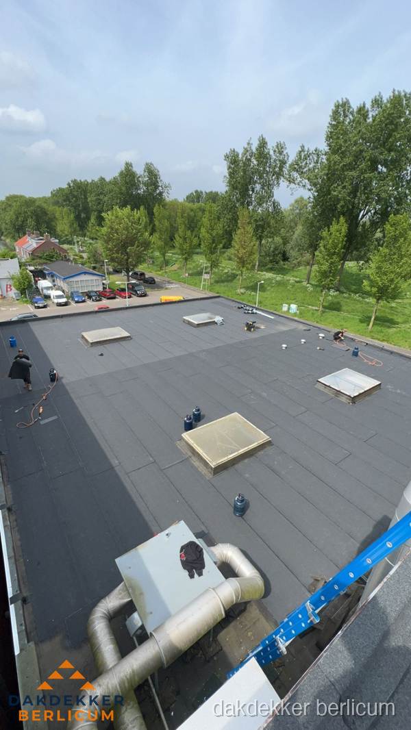 Dakdekker aan het werk op groot plat dak met bitumen in Berlicum
