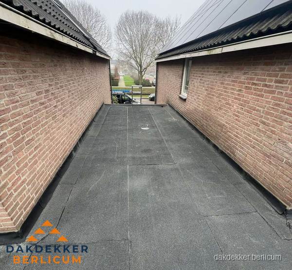 Plat dak met bitumen dakbedekking tussen bakstenen muren in Berlicum Plat dak met bitumen dakbedekking tussen bakstenen muren in Berlicum